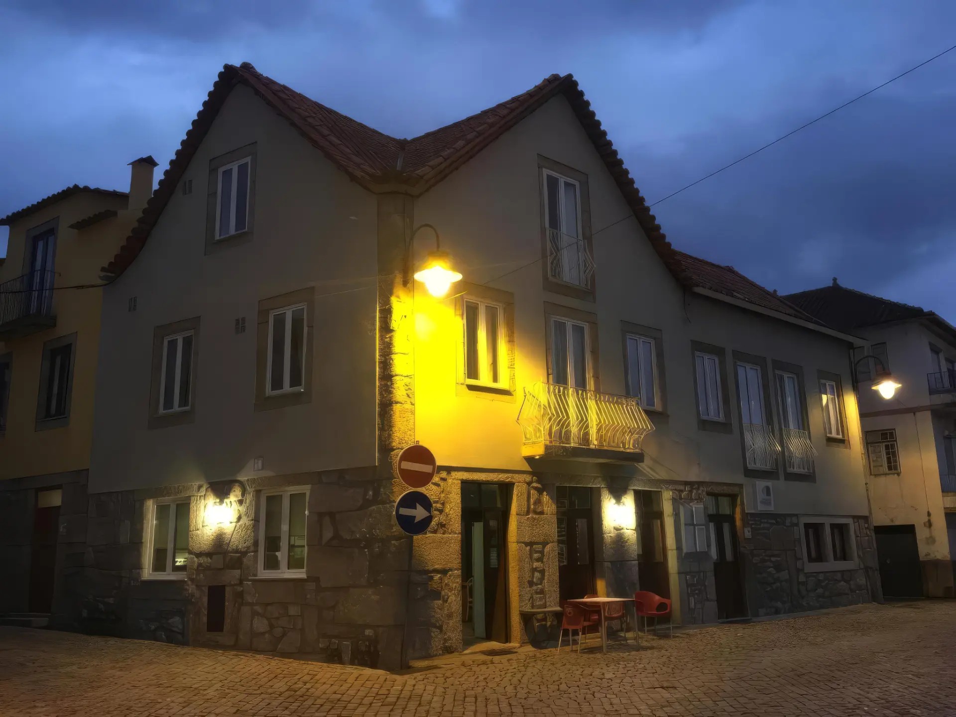 Fachada das Casas do Terreiro ao anoitecer, com esplanada e candeeiros acesos