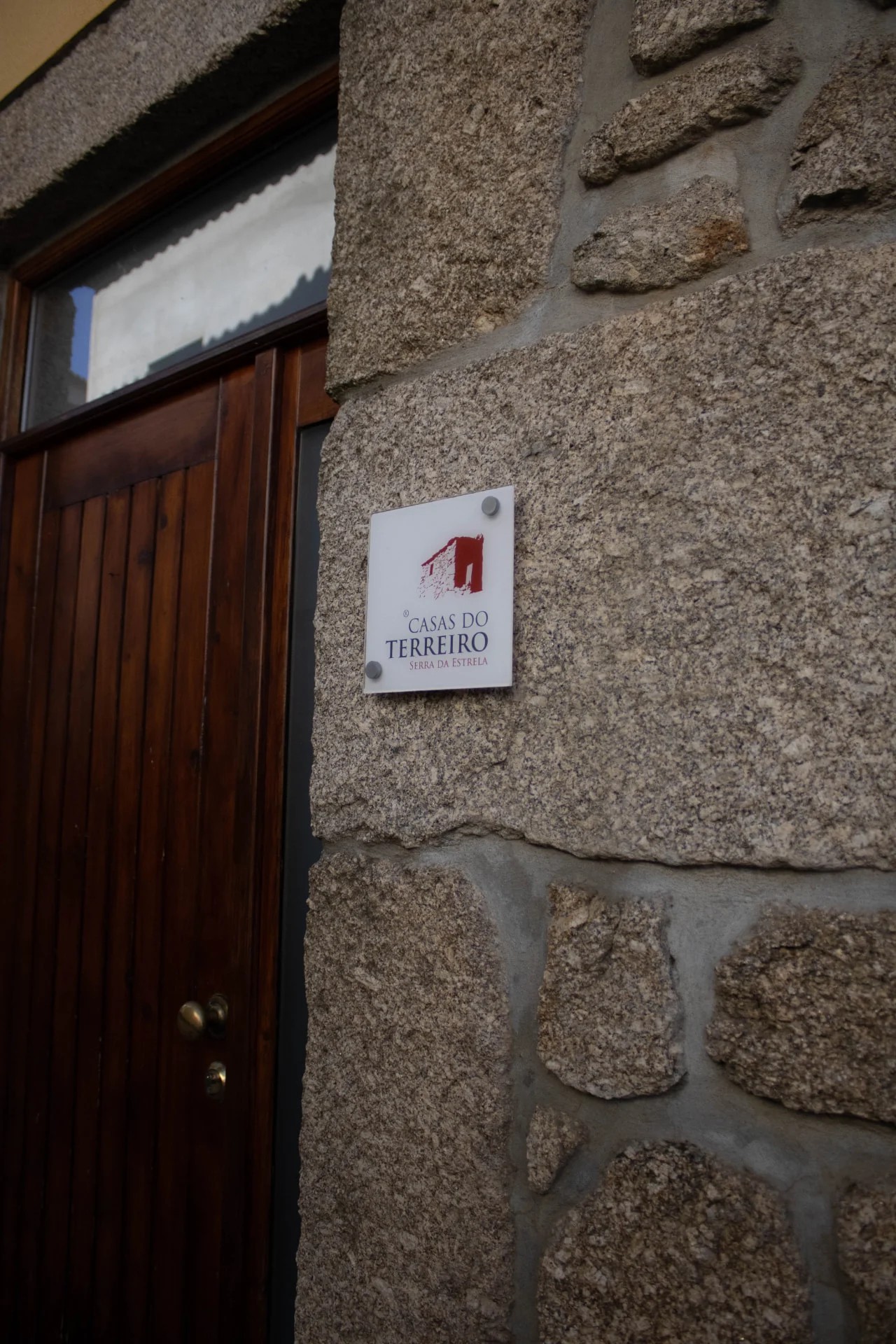 Placa das Casas do Terreiro em parede de granito, ao lado da porta de madeira